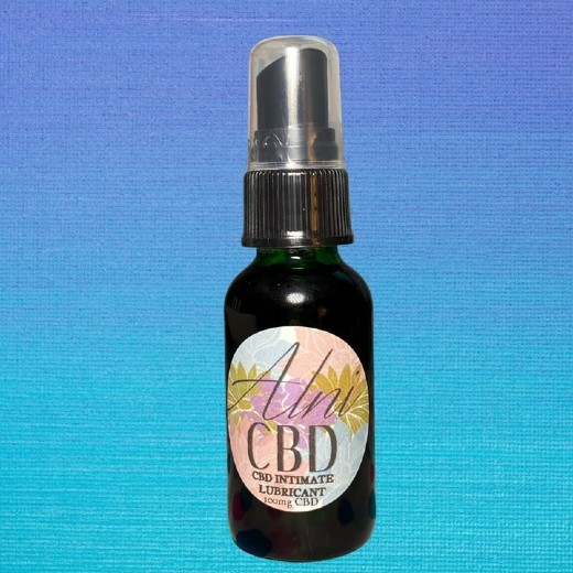 Image of Alni Body Care LLC's CBD lubricant. The bottle is a very dark green with pink and blue circular label saying 'Alni CBD' on the bottle. Image used with permission from Alni Body Care LLC.