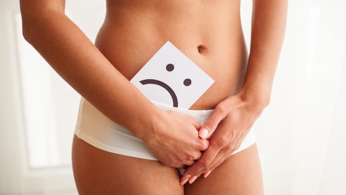 Image of a person with white underwear and a piece of white paper with black marker drawing of a sad face around the genital area.