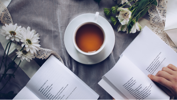 Image of a bunch of books on a table with a cup of tea.