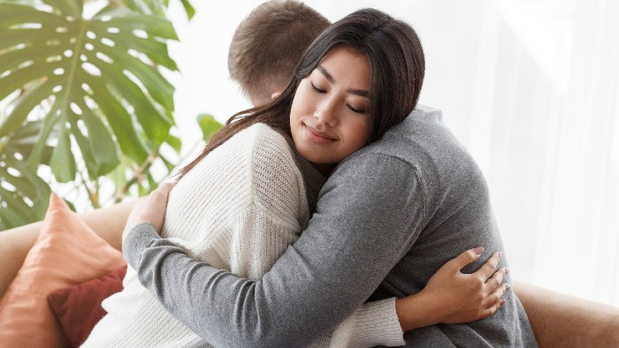 Image of two people hugging, with a look of peace and relief on their face.